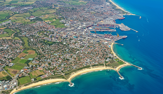 a detailed overhead view of a diverse city with residential industrial and agricultural zones and a clear blue ocean